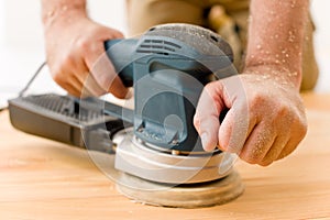 Home improvement - handyman sanding wooden floor photo