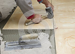 Home improvement, renovation - construction worker tiler is tiling, ceramic tile floor adhesive, trowel with mortar