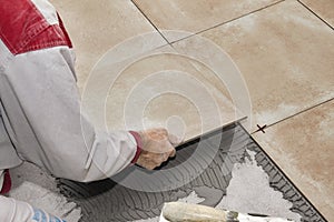 Home improvement, renovation - handyman laying tile with level