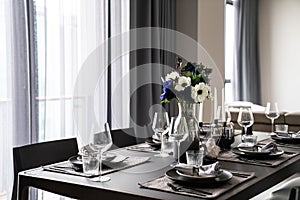 Home Inerior with dining room table setting with gold stainless tableware black cutlery setting on nartual marble top / interior