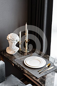 Home Inerior with dining room table setting with gold stainless tableware and cutlery setting on nartual marble top. interior