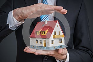 Home insurance concept. Man is holding model of house