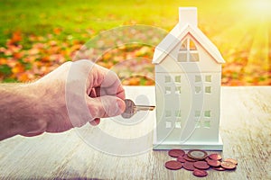 Home insurance concept. Safety of family and home. key in hand closes miniature house with money coins. Save property in house
