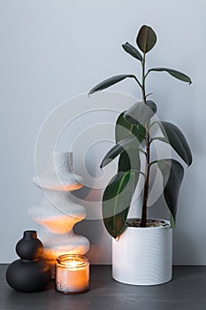 Home interior with decor elements. White and black decorative handmade vase and burning candle on a background of gray wall