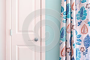 Home interior showing colonial closet door with turquoise curtain decor and light blue painted wall