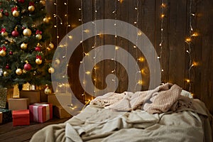 Home interior with wooden wall, bed, christmas tree and lights, winter holiday concept