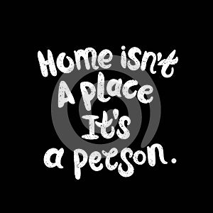 Home isn`t a place it`s a person. White letters on chalkboard background. Modern Brushed Lettering. Decorative lettering. Quote.