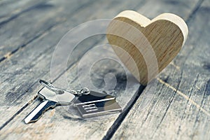 Home key with house keychain and wooden heart mock up on vintage wood background, home sweet home concept