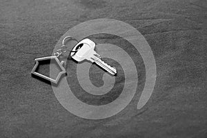 Home key with house keyring on bed in black and white, property concept, copy space