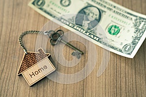 Home key with house keyring on dollar bill stack