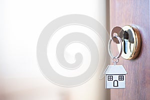 Home key with house keyring in the door keyhole