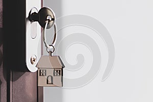 The home key with house keyring in the door keyhole with copy space