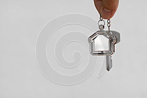 Home key with house keyring hanging with white wall background