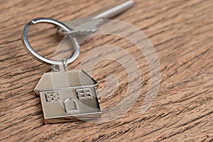 Home key with house keyring or keychain on wooden table using as home ownership, mortgage or buy and sell property and real estate