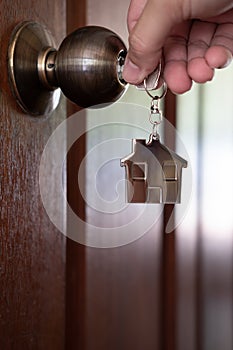 Home key with house keyring in keyhole on wooden door