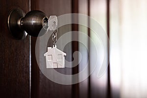 Home key with house keyring in keyhole on wooden door