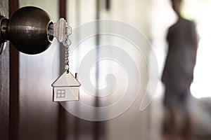 Home key with house keyring in keyhole on wooden door