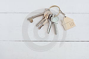 Home key with house keyring on white wood table background, property concept