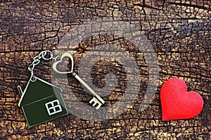 Home key with love house keyring decorate with mini heart on wood background, sweet home concept