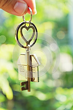 Home key with love house keyring hanging with blur garden background