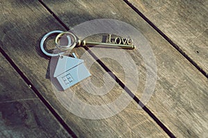 Home key with love house keyring on wood background