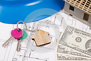 Home keys, currencies dollar, electrical construction diagrams and small house under contruction. Building or buying home