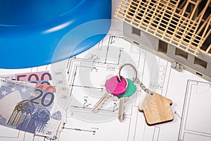 Home keys, currencies euro, electrical construction diagrams and small house under contruction. Building or buying home