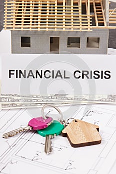 Home keys, dollar and inscription financial crisis on housing plan. House under contruction. Crisis of real estate market. Reduced