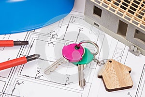 Home keys, electrical construction diagrams and small house under contruction. Building or buying home