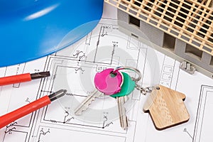 Home keys, electrical construction diagrams and small house under contruction. Building or buying home