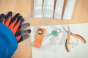 Home keys with electrical drawings, protective blue helmet with gloves and orange work tools, concept of building home