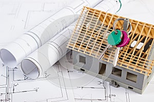 Home keys, small house under construction and electrical drawings, building home concept