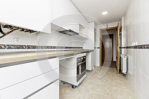 Home kitchen with oak-colored wooden countertop and access door of the same material with an aluminum radiator behind