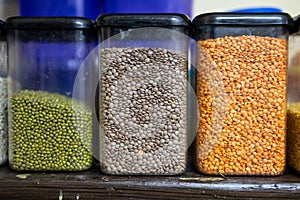 home kitchen shelf displaying assorted dried beans and lentils in jars