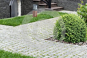 Home landscaping. Backyard with granite paving stones, green grass and street lights.