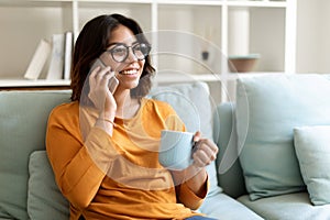 Home Leisure. Smiling Arab Woman Talking On Cellphone And Drinking Coffee