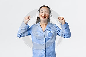 Home leisure, weekends and lifestyle concept. Happy smiling woman stretching after good nap, listening music in wireless