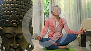 Home lifestyle - beautiful and happy mature woman with gray hair on her 50s doing yoga meditation exercise at Asian deco bedroom