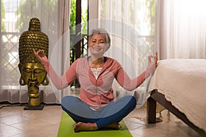 Home lifestyle - beautiful and happy mature woman with gray hair on her 50s doing yoga and meditation exercise at Asian deco