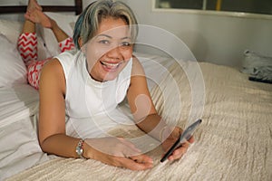 Home lifestyle portrait of attractive and happy middle aged woman on her 50s using internet mobile phone in bed relaxed and