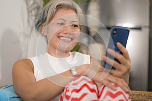 Home lifestyle portrait of attractive and happy middle aged woman on her 50s using internet mobile phone at living room couch