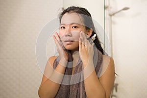 Young beautiful and happy Asian Korean woman applying serum facial skin care and face treatment in the bathroom enjoying morning photo