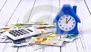 Home loan concept. Euro banknotes, an alarm clock in the form of a house and a calculator