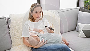 At home, a loving mother breastfeeds her baby while watching television, bonding together in the living room