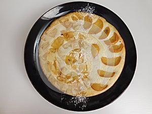 Home made apple cake in the black plate served on table