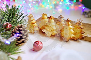 Home made bakery on christmas lights background. Baked fir trees. New year atmosphere. Holidays celebration. Food art.