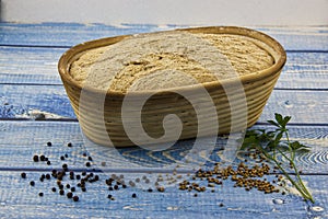 home made bread, risen wholemeal dough in a wood trug on blue plank table, pimiento, coriander, parsley