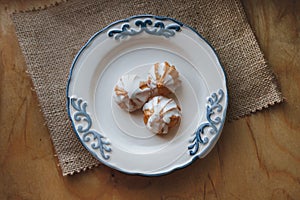 Home made choux cream on white plate. Over on wood table. Top view. with a white glaze. on wooden background