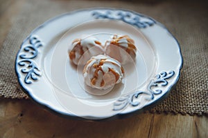 Home made choux cream on white plate. with a white glaze. Over on wood table. Top view.