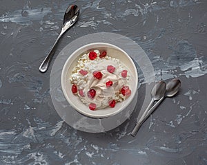 Home-made cottage cheese with sour cream of cream with berries dried cherries in a deep white plate on a gray background